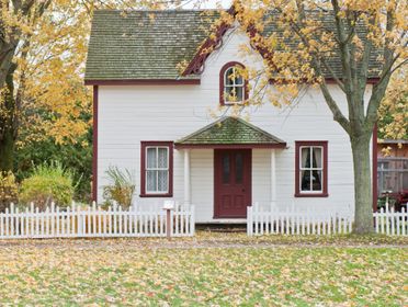 Picturesque traditional house with autumn foliage and a white picket fence in London, Ontario.