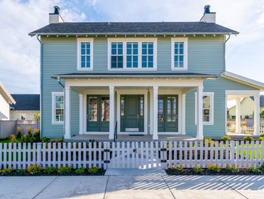 A modern suburban house with a charming white picket fence in a quiet residential neighborhood.