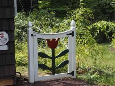 Whimsical garden gate with tulip design in lush greenery, Doylestown, PA.