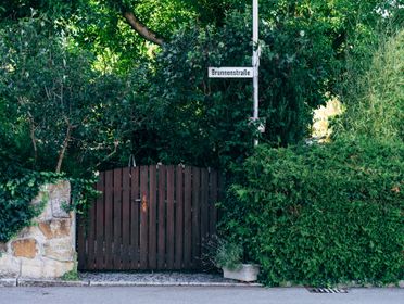 Rustic wooden gate surrounded by lush greenery and street sign on a summer day.
