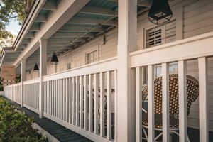Inviting porch with wicker chairs, white railings, and hanging lanterns creates a cozy atmosphere.