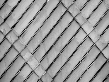 Close-up of a chain-link fence in black and white showcasing a textured pattern.