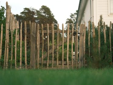 A rustic wooden fence surrounds a quaint countryside yard, offering a peaceful rural scene.