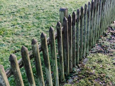 A rustic, weathered wooden fence in a grassy, outdoor garden setting. Perfect for nature photography.