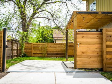 Sunlit wooden fence and patio gate in a peaceful backyard setting.
