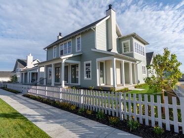 A charming suburban house with a white picket fence and clear skies, perfect for family living.