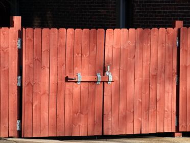 Rustic red wooden fence with a metal latch, ensuring safety and security outdoors.